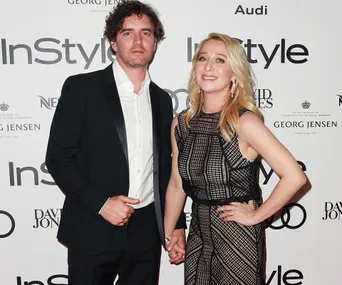 Couple dressed in formal attire, holding hands at an InStyle magazine event backdrop.
