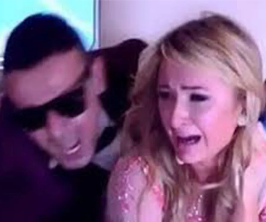 Two people in a tense scene; one wearing sunglasses, and the other appears distressed.