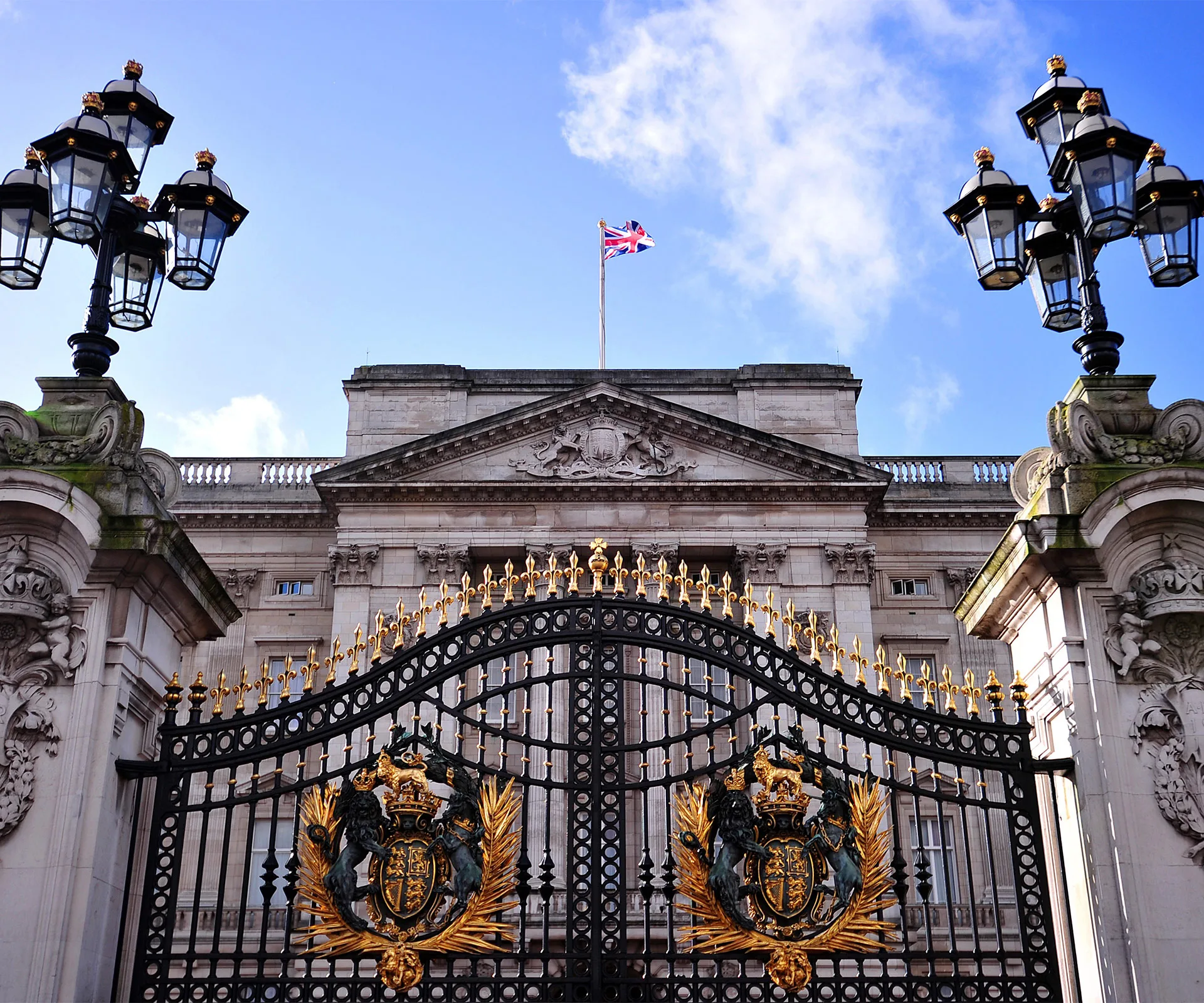 Buckingham Palace with ornate gates and a Union Jack flag flying atop the building.