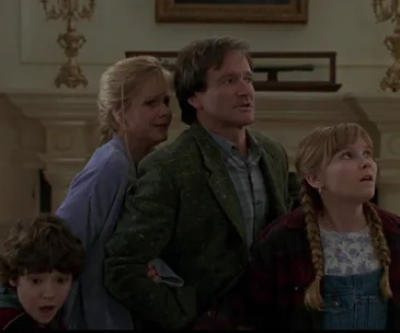 A group of four characters from the original "Jumanji" film look surprised and concerned, standing indoors.