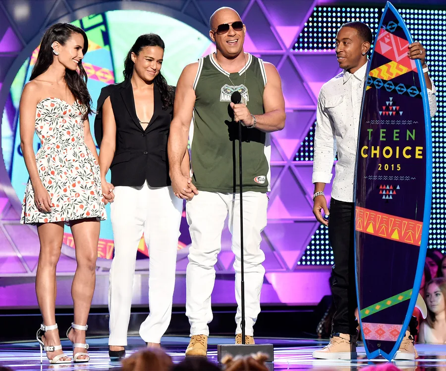 Cast from "Fast & Furious" on stage at the 2015 Teen Choice Awards holding hands and surfboard award.