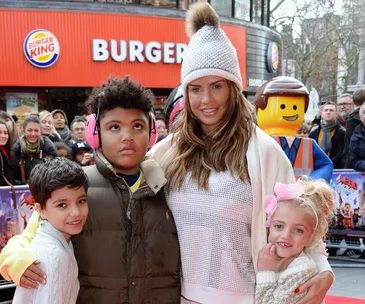 Group with kids and a woman at a public event, Lego figure in background, Burger King sign visible.