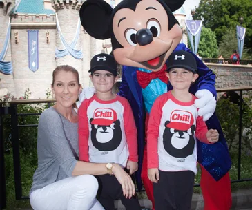 Celine Dion with her twin sons and Mickey Mouse at a theme park.