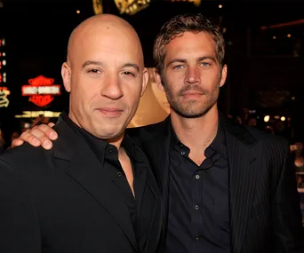 Two men in formal wear, one with a shaved head and the other with short hair, posing together at an event.