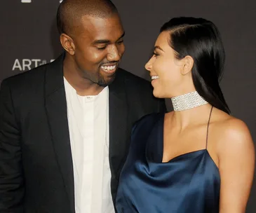 A couple smiling at each other at a formal event, wearing elegant attire.