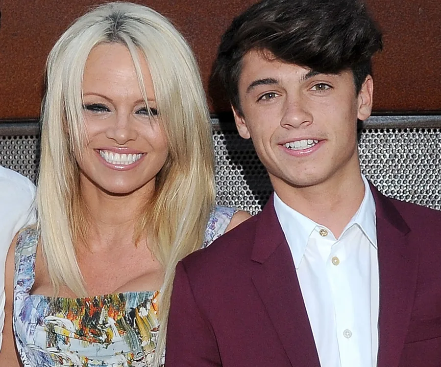 "Pamela Anderson smiling with her son Dylan Lee, both dressed formally."