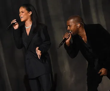 Rihanna and another artist performing on stage with microphones.