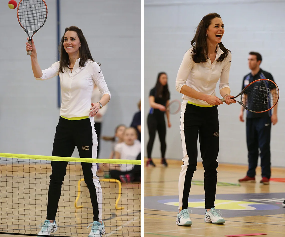 Woman playing tennis indoors, smiling and holding a racquet, in athletic attire.