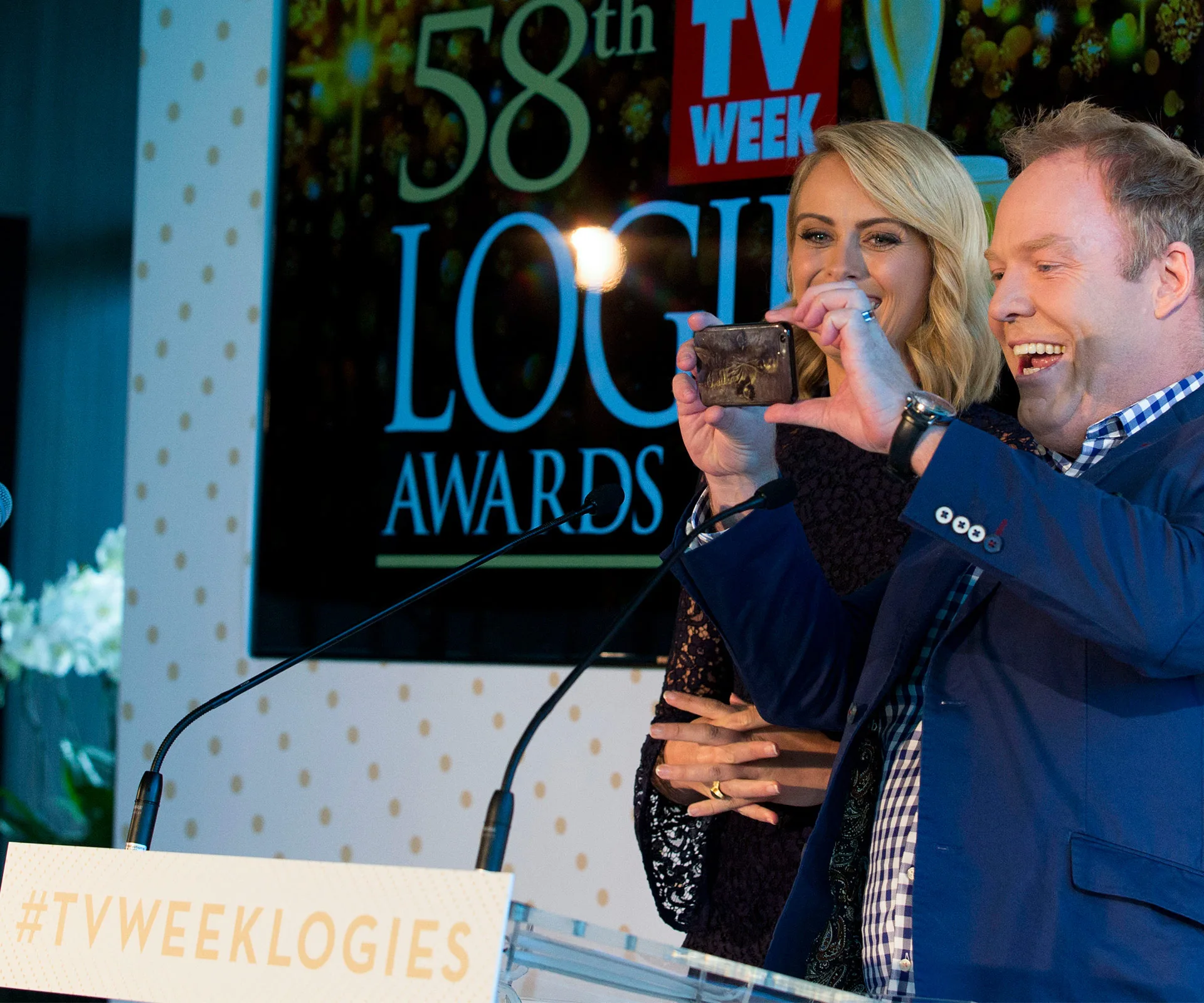 Two people on stage, smiling and taking a selfie at the 58th TV Week Logie Awards press event.