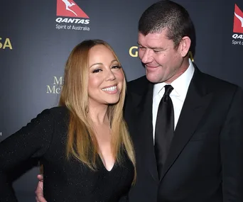 Couple smiling on a red carpet, with one person wearing a black dress and the other in a suit.