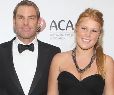 Man and young woman posing at an event, both smiling, with a logo in the background.