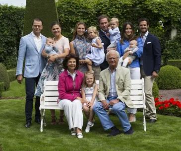 Swedish royal family portrait in a garden, showing multiple adults and children dressed in summer attire.