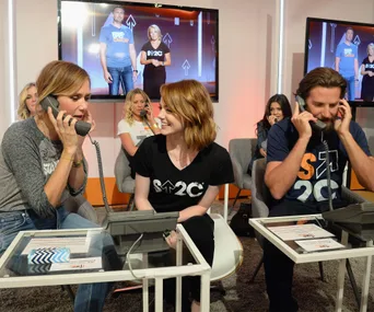 Celebrities at Stand Up to Cancer event answering phones and engaging in conversation in a studio setting.