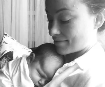 A woman holds a sleeping baby close to her chest, both appearing peaceful and serene.