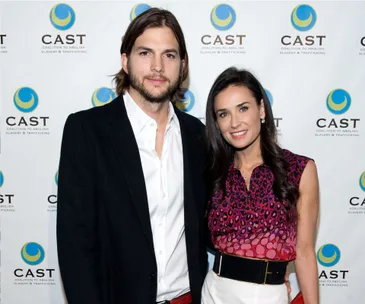 Two people posing for a photo at a CAST event, with a logo backdrop.