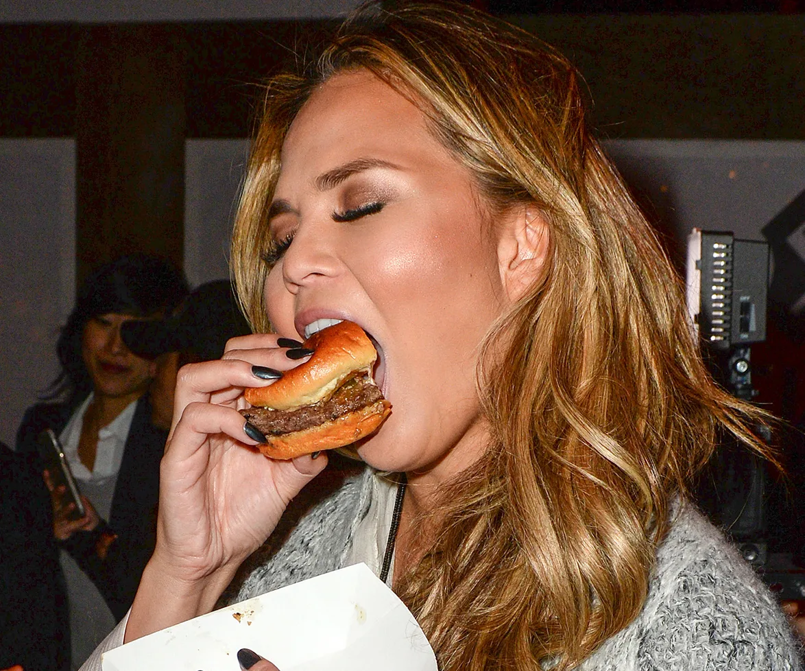 Chrissy Teigen enjoying a cheeseburger