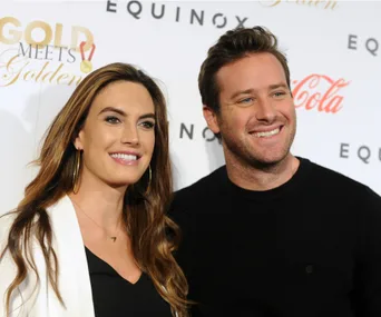 A couple smiling at a red carpet event; backdrop features logos for "Gold Meets Golden" and "Equinox".