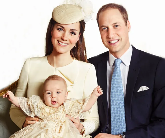 A family dressed formally with a baby in a lace christening gown, smiling at the camera.