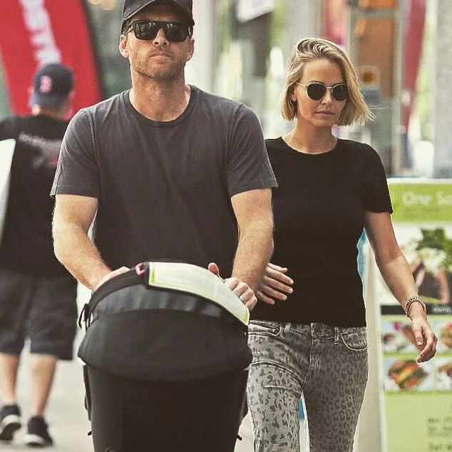 A man and woman in sunglasses walk together, pushing a stroller down a city street.