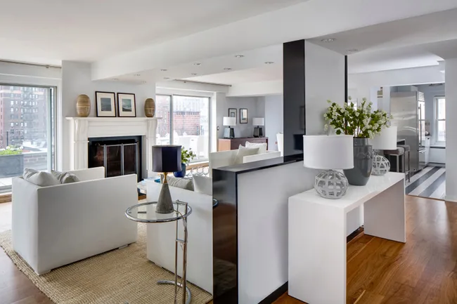 Modern living room with white sofas, fireplace, large windows, and decorative lamps on wooden floors.