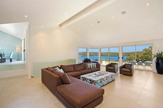 Spacious living room with brown sectional sofa, large windows, and beautiful ocean view.