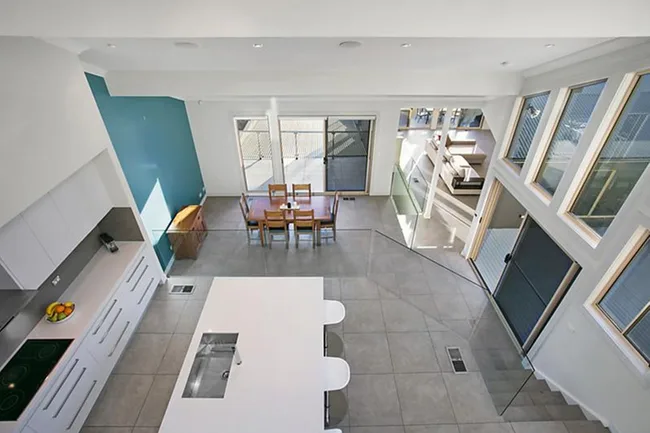 Modern open-plan kitchen and dining area with white cabinetry, island, and large windows allowing natural light.