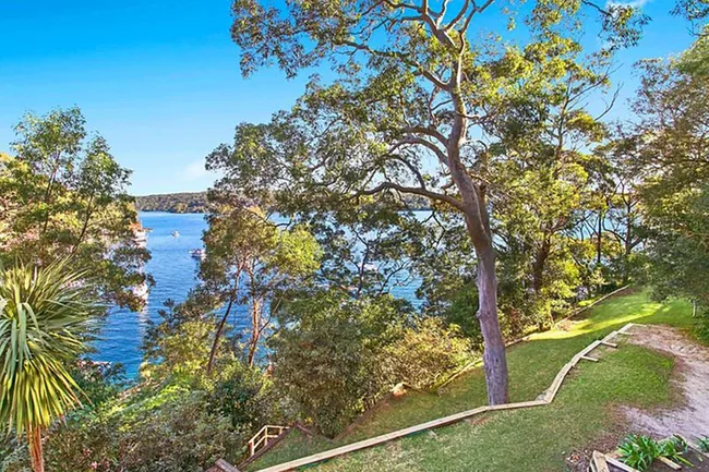 View of a serene lake surrounded by lush green trees and a clear blue sky.