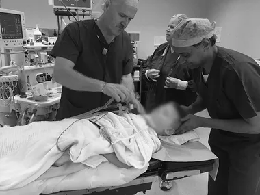 Doctors preparing a young child for surgery in an operating room.