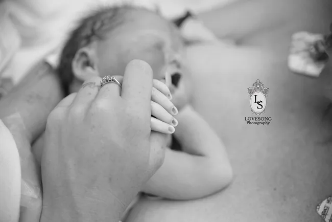 A newborn baby holds a parent's hand.