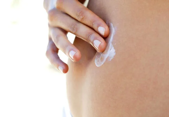 "Close-up of a hand applying lotion to skin."