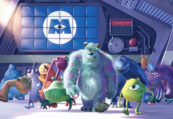 Monsters from "Monsters, Inc." including Sulley and Mike stand in front of a company logo in a factory setting.