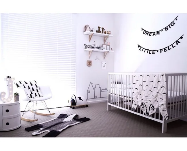 Minimalist nursery with a white crib, rocking chair, and "Dream Big Little Fella" wall decor.