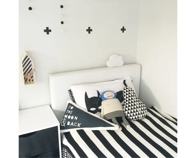 Monochrome children's room with striped bedding, cushions, and wall decor, featuring "To the Moon & Back" text.