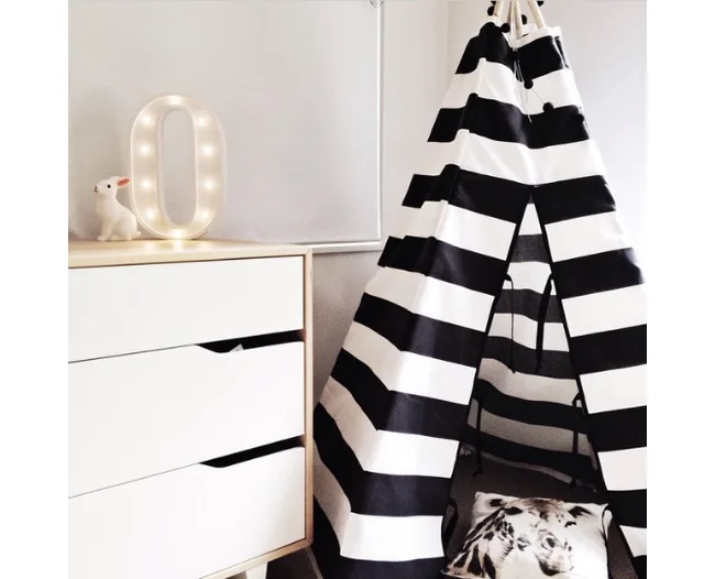 Black and white striped teepee in a room with a white dresser and a lit marquee letter "O".
