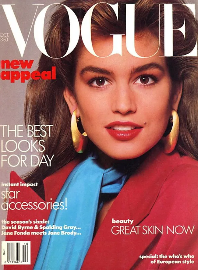 Cover of Vogue magazine featuring a model with bold earrings, blue scarf, red jacket, and vibrant makeup.
