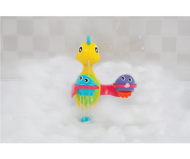 Toy whale fountain in a bubble bath, with two colored cups on either side, water flowing from top.