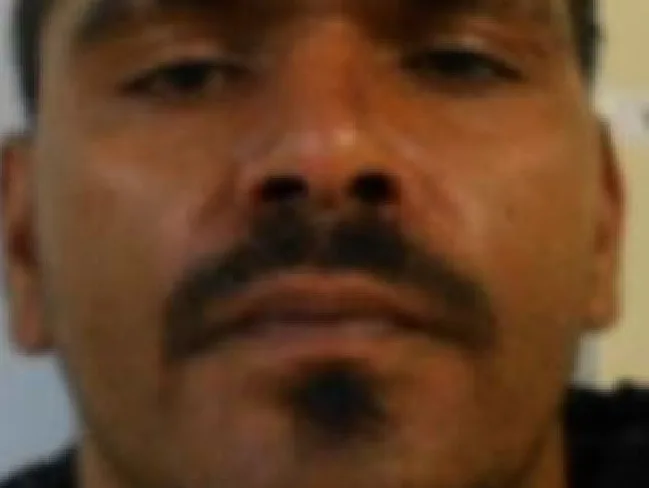 A close-up image of a man with facial hair looking directly at the camera.