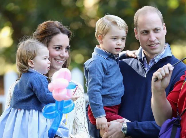 A family with two young children enjoying an outdoor event, one holding a balloon animal.