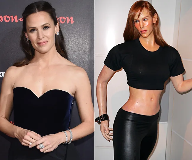 A woman in a dark strapless dress beside a wax figure in black crop top and pants, posed similarly.