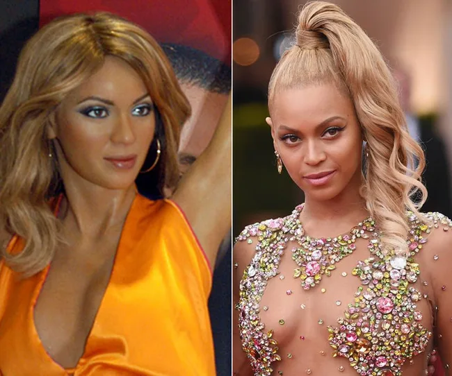 A wax statue of a woman in an orange top alongside a woman with blonde hair in a jeweled dress.