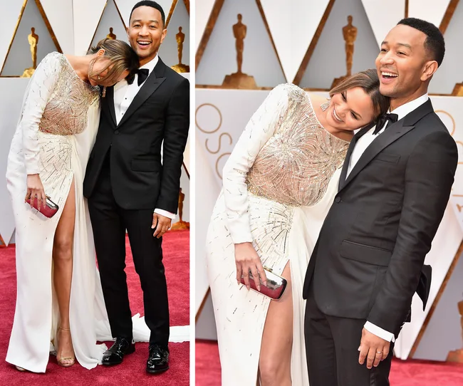 A smiling couple in formal attire poses on the red carpet at an awards event.