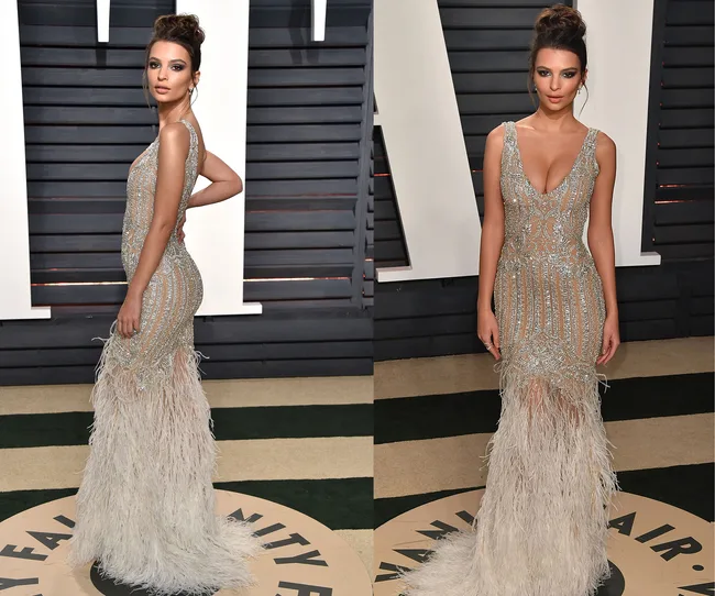 Woman in a silver, feathered gown poses confidently at a Vanity Fair event.