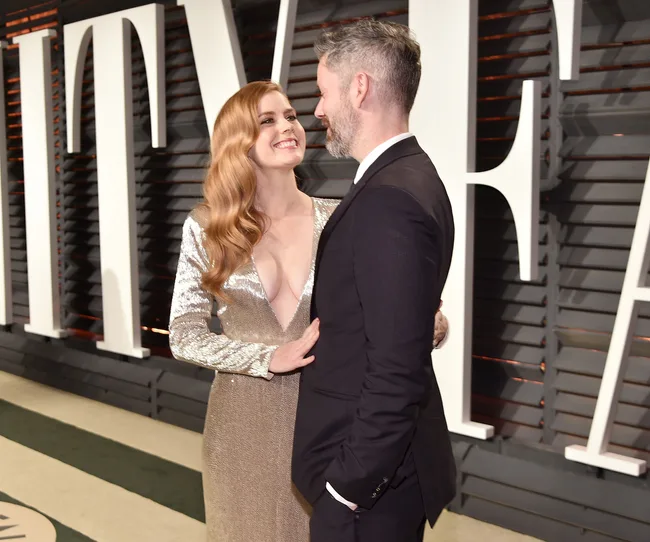 A woman in a sparkling dress and a man in a suit pose together at an elegant event.