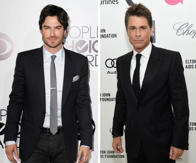 Two men in suits at a red carpet event, standing in front of promotional backdrops.