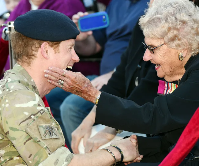 Royal in military uniform meeting elderly woman warmly in Sydney.