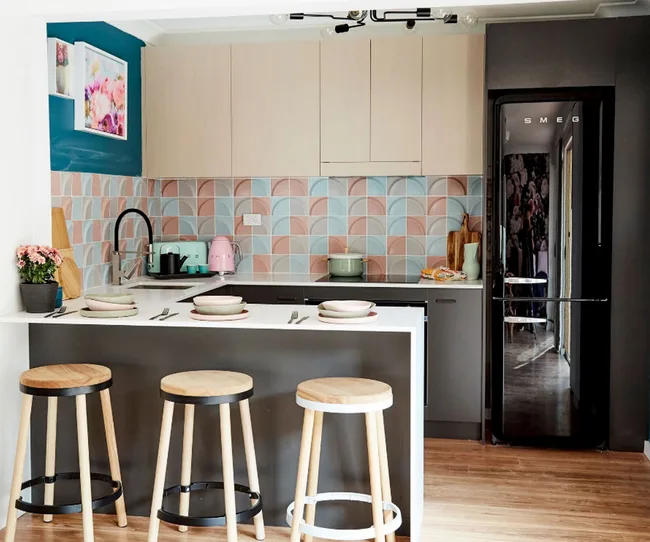 Modern kitchen with patterned backsplash, island with stools, and retro-style fridge.