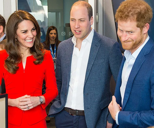 Three people in business attire smiling and talking indoors at an event.