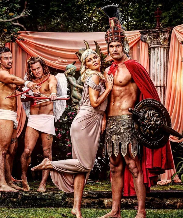 Warrior in Roman attire with shield, woman in gown, and two cupids with bows in elaborate outdoor setting.