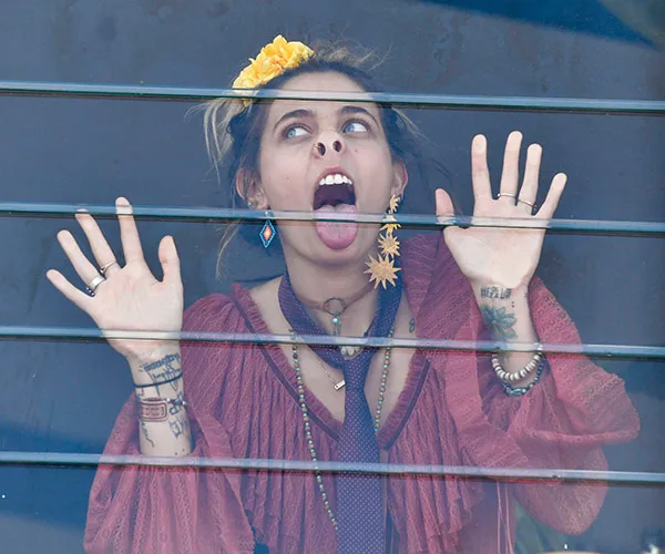 Paris Jackson playfully presses her face against a glass window, making a funny expression with her tongue out.
