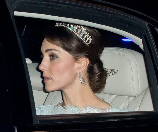 Kate Middleton wearing a pearl and diamond tiara, looking out of a car window.